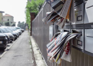 Many advertising leaflets are hanging from an overloaded letterbox